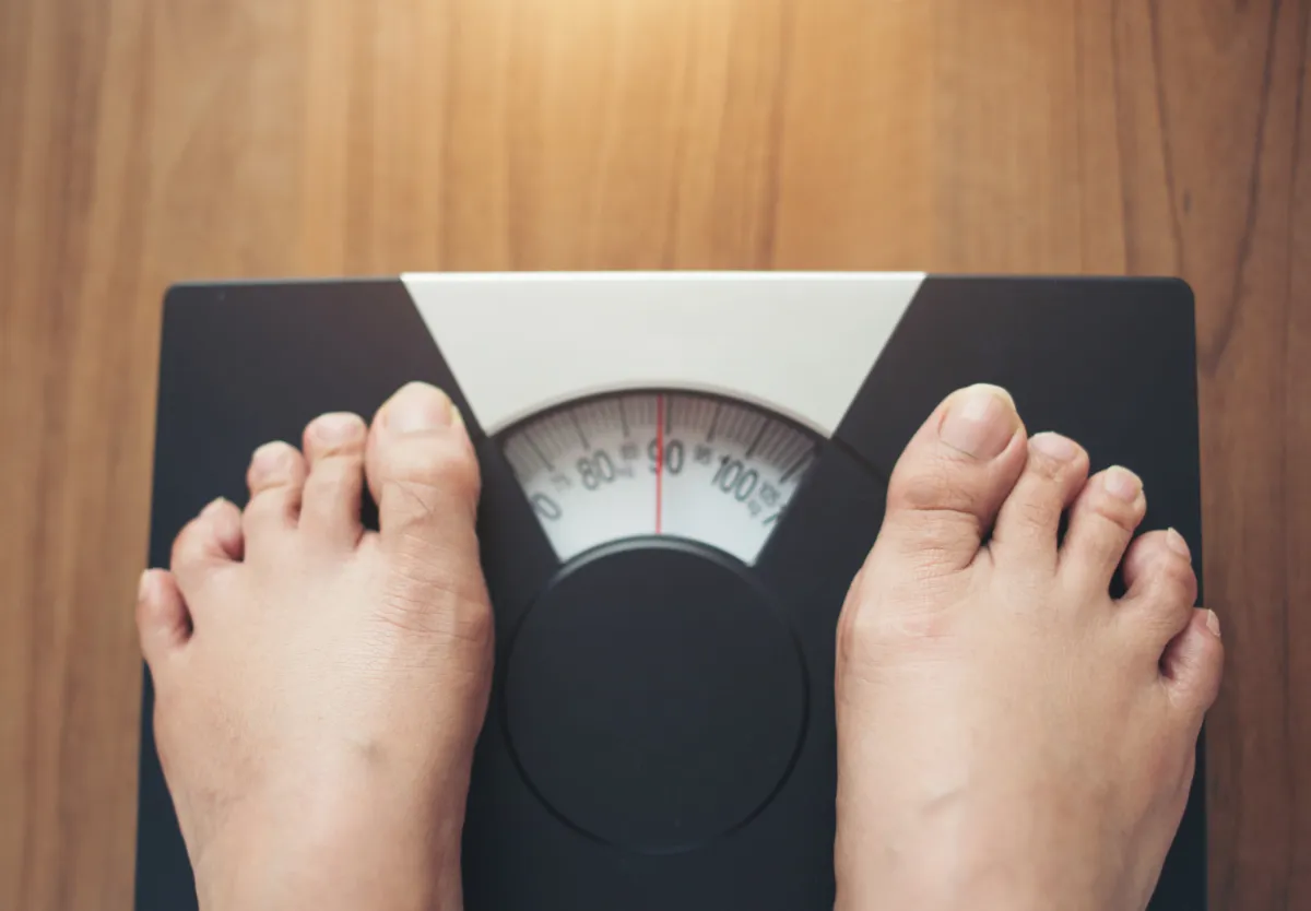 A person standing on a weighing scale representing Ayurvedic weight management and metabolism improvement