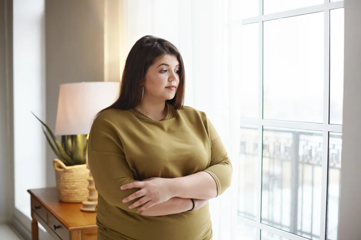 Woman reflecting on weight concerns, representing holistic Ayurvedic support for metabolism and hormonal balance