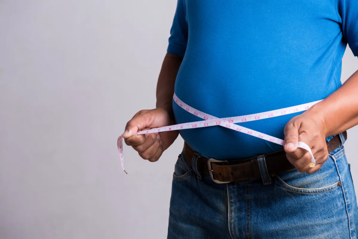 Measuring abdominal fat, highlighting Ayurvedic Panchakarma treatment for natural weight loss and metabolic balance