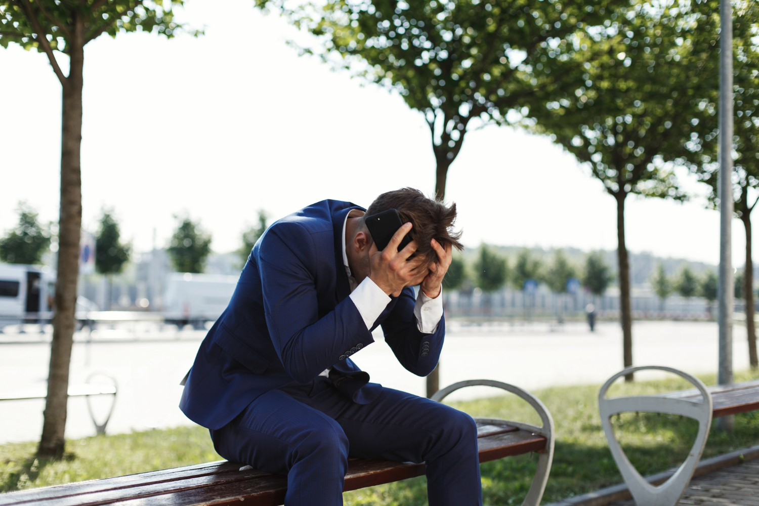 Man sitting on a bench experiencing work-related stress and emotional overwhelm